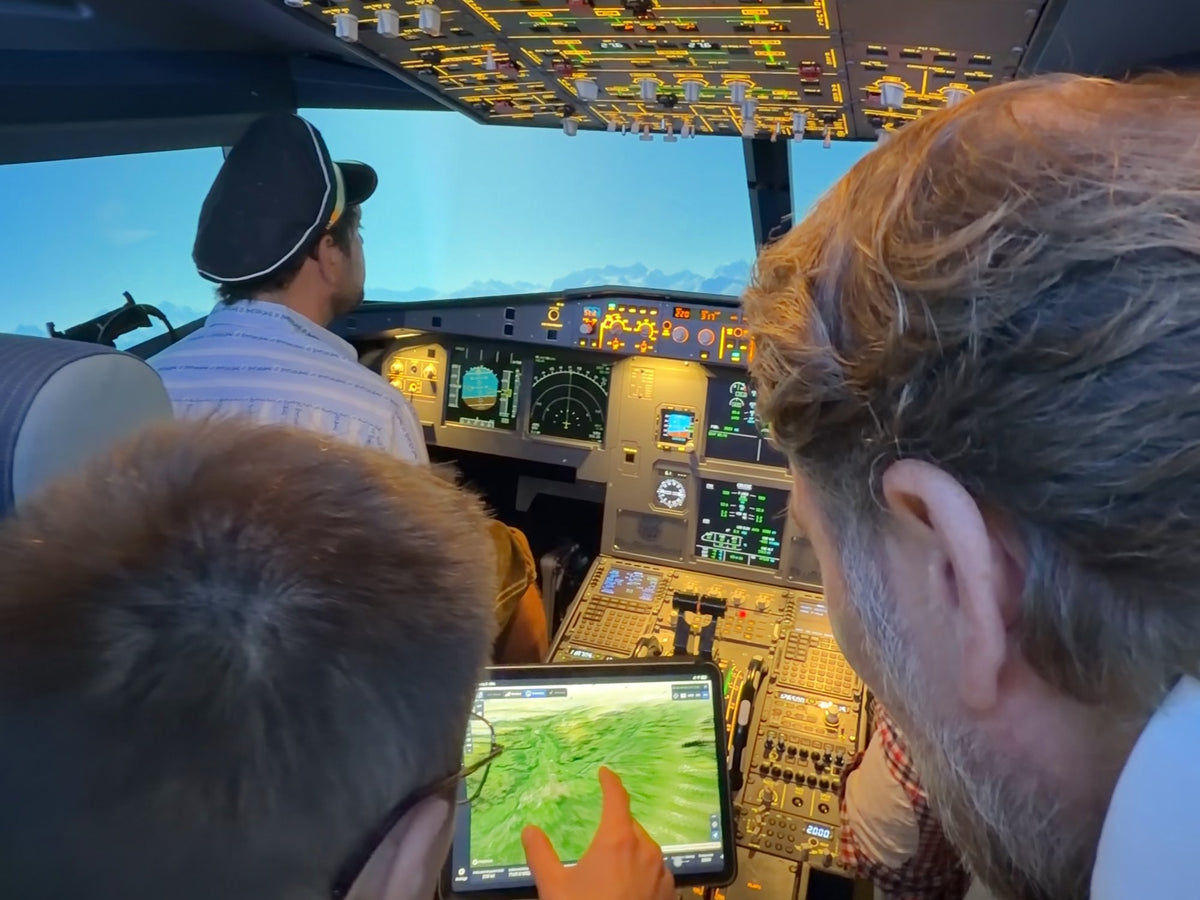 JGA-Gäste mit Pilotenmütze planen den Flug am Tablet im A320 Cockpit
