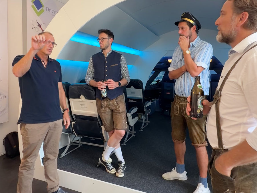 JGA-Gruppe in Lederhosen mit Pilotenmützen in der Kabine des A320 Flugsimulators