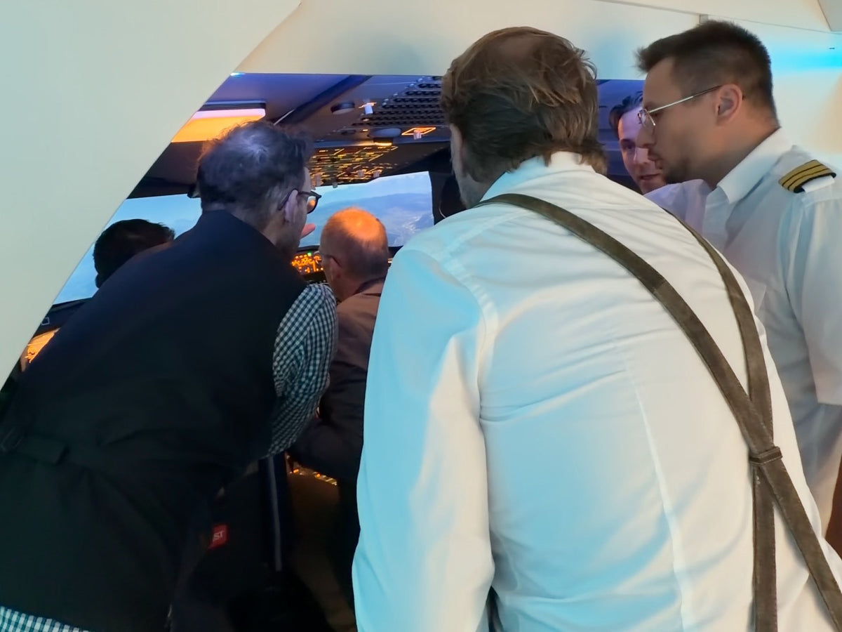 JGA-Gäste in Lederhosen schauen ins Cockpit des A320 Flugsimulators